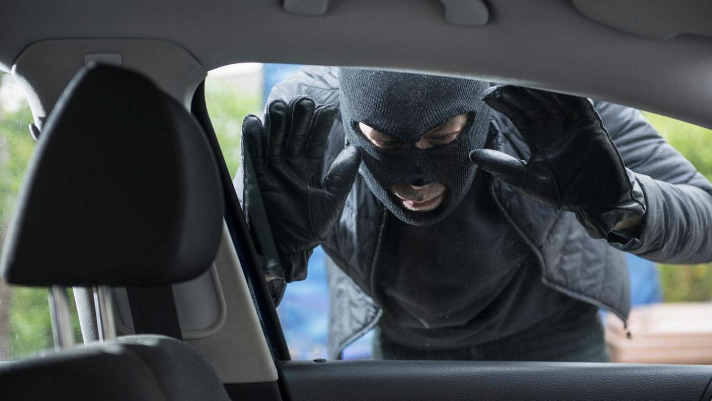 Man in balaclava looking in car