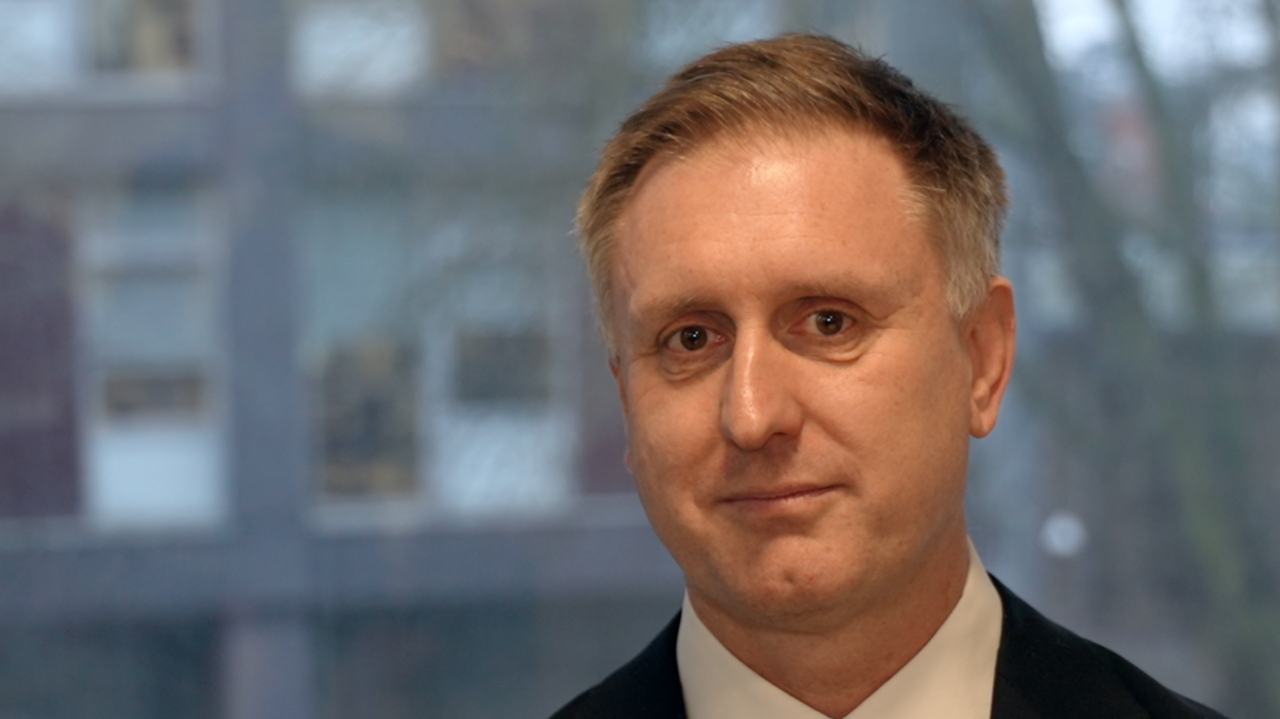 Ed Garrett with short light brown hair wearing a shirt and tie. He is looking into the camera

