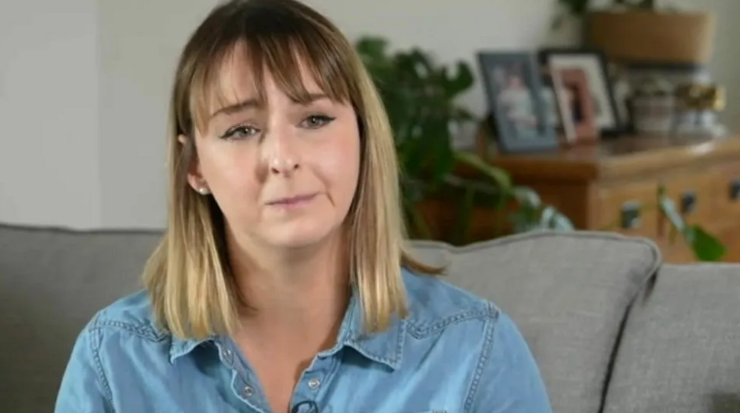 Crystal Owen wearing a blue top and sitting on a grey sofa