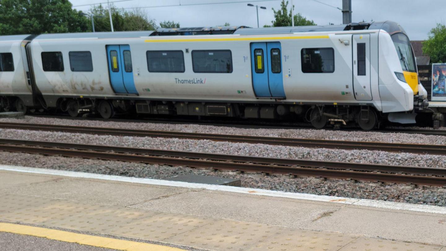 The station platform at Huntingdon with a white Thameslink train arriving on the adjacent platform