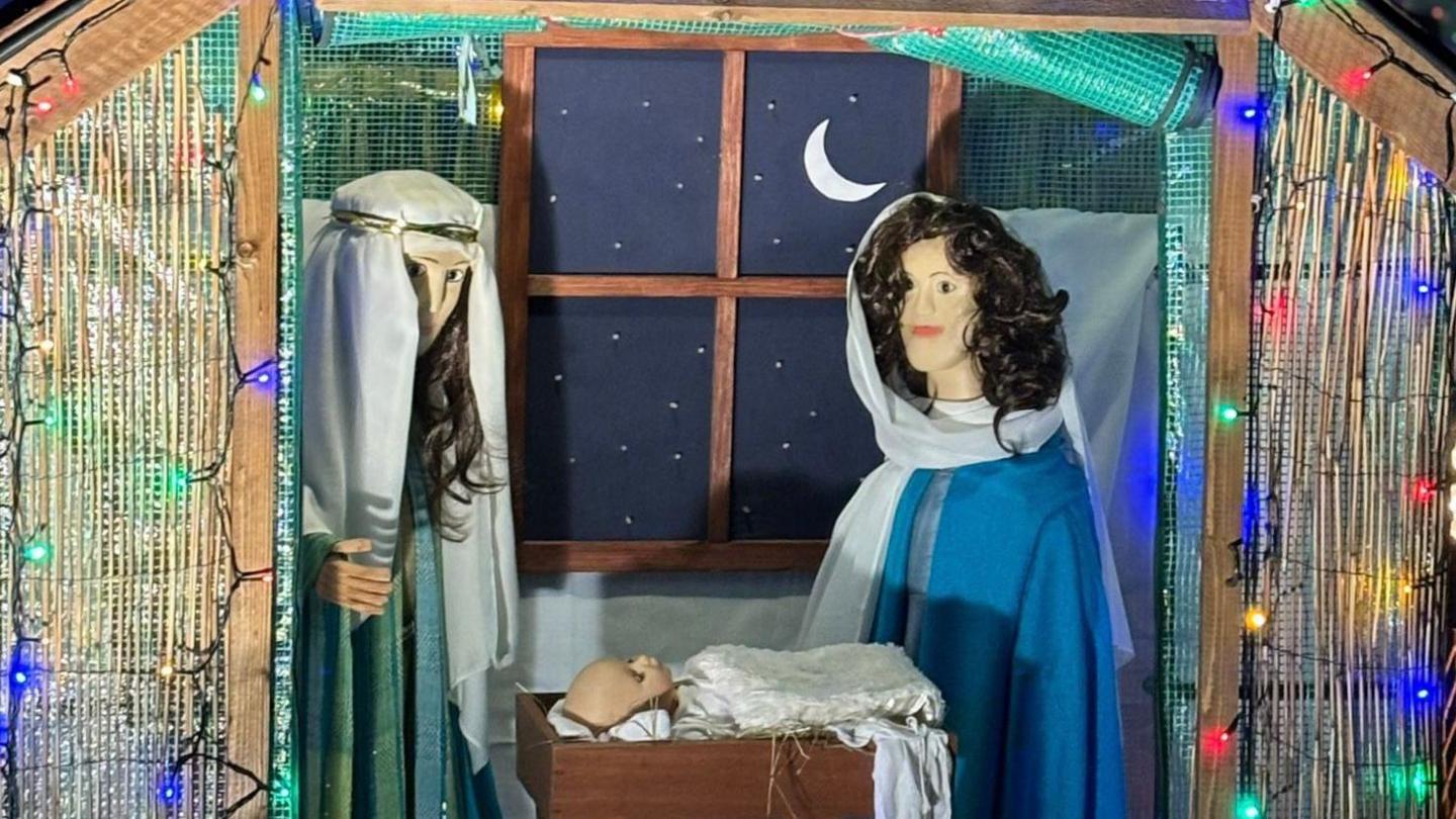 A nativity display showing Mary and Joseph with the baby Jesus inside a makeshift stable. The figurines are looking over a cradle.