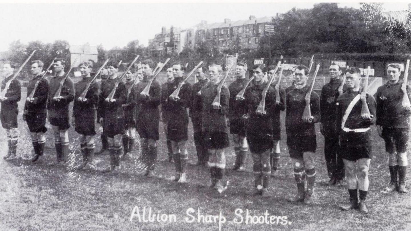 A black and white photo of men holding rifles.