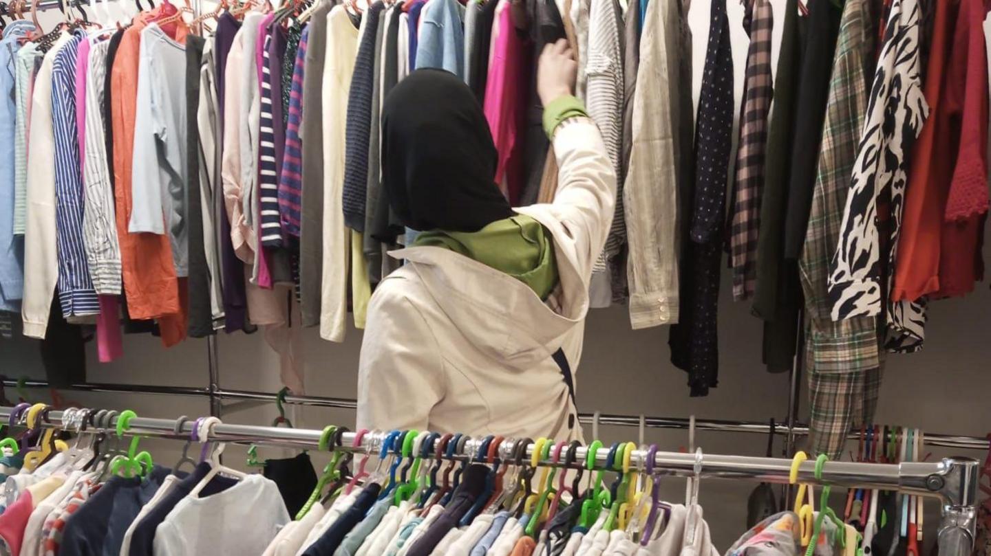 Racks of clothes and a woman looking through them