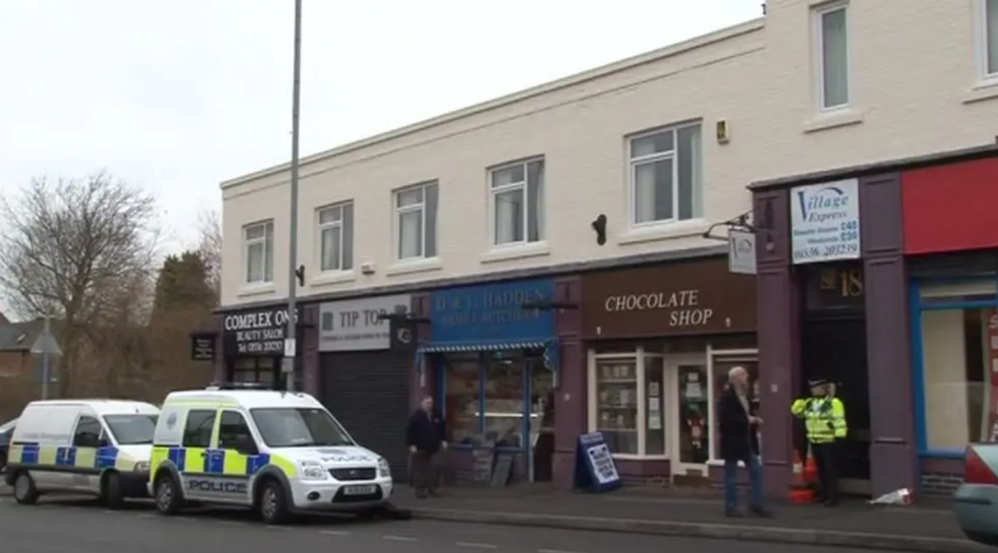 Two police vehicles outside a row of shops 