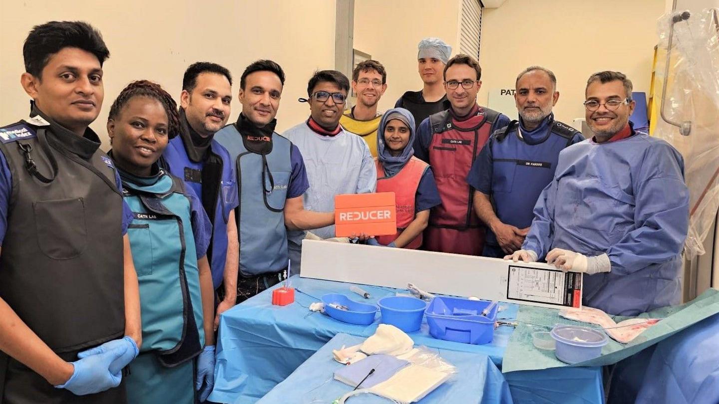 Hospital staff in scrubs around a table with medical devices