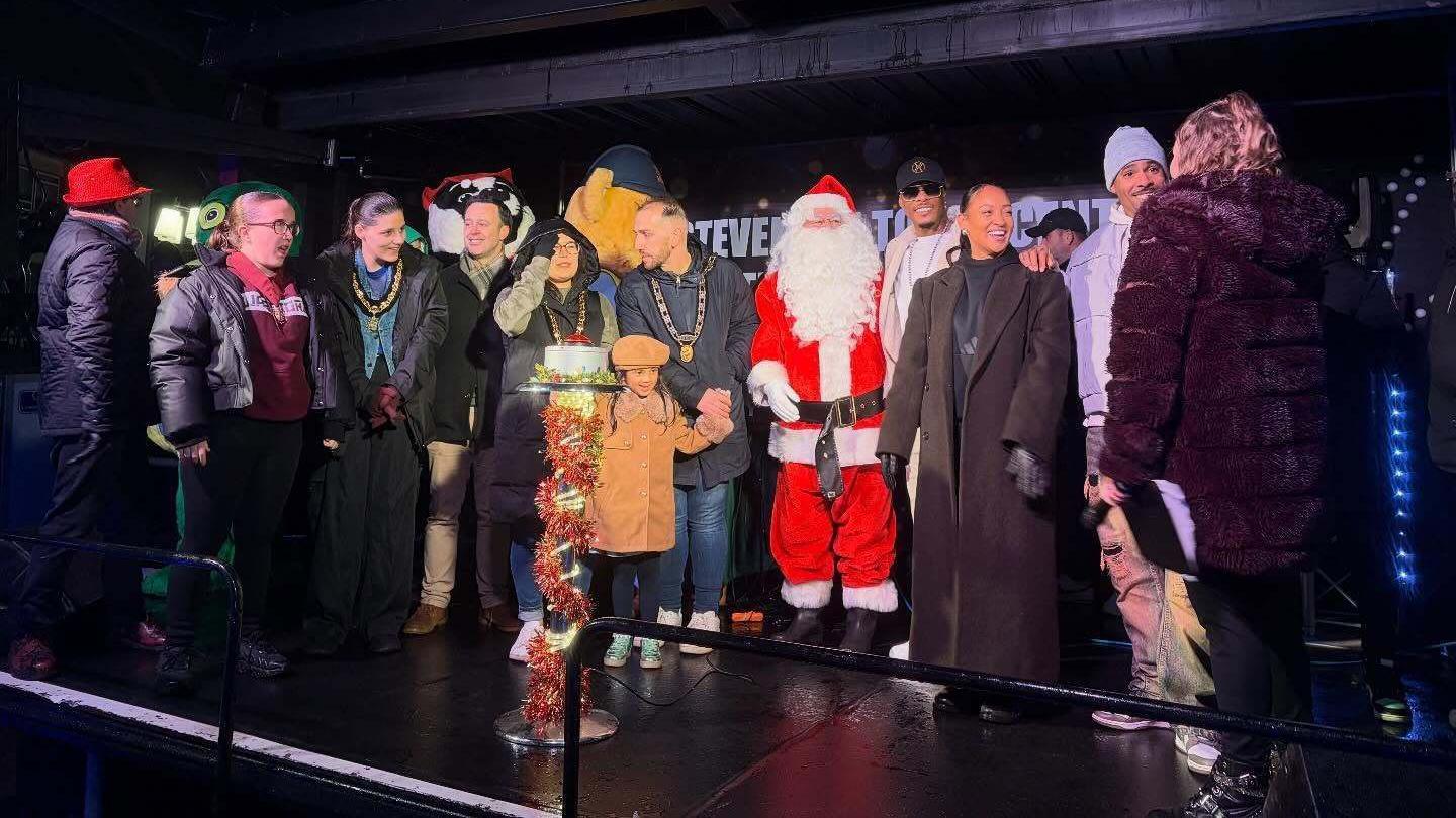 A crowd on a stage. Some adults are wearing ceremonial chains. Santa is with them, as is a young girl.
