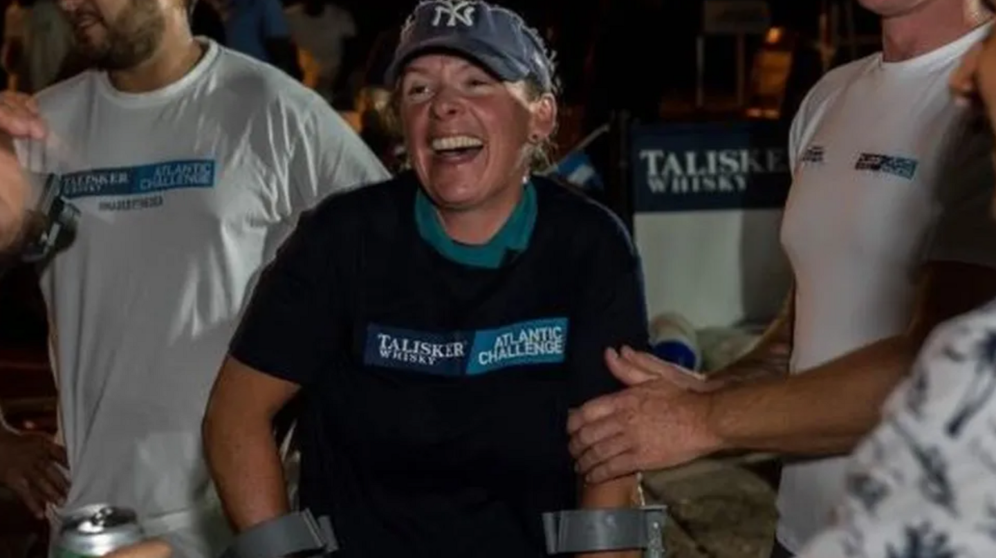 Kelda Wood in a baseball cap and black T-shirt, celebrating completing a crossing of the Atlantic with men wearing white T-shirts