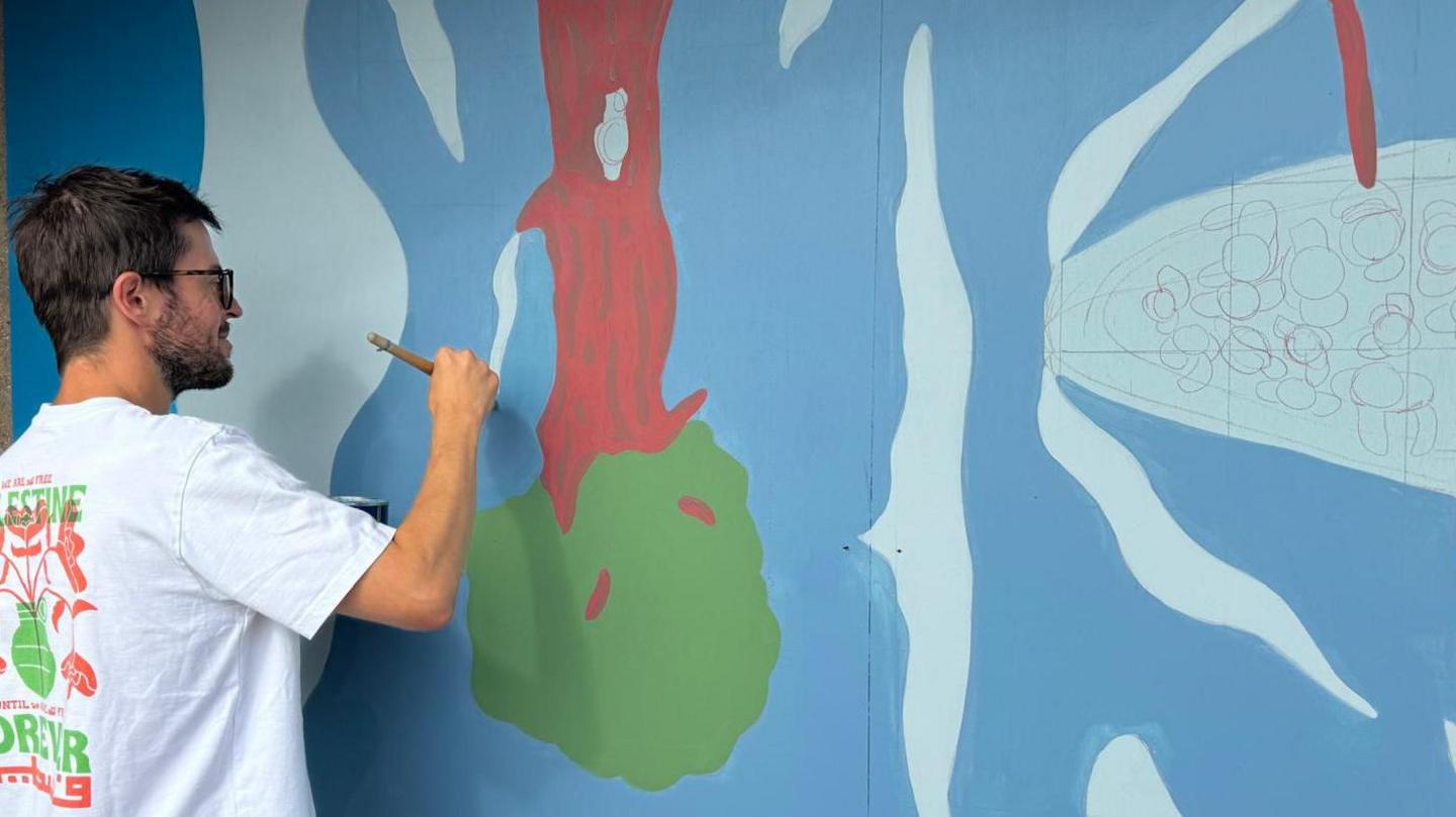 Artist Will Bertram painting his mural