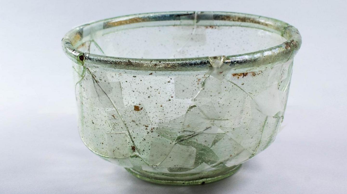 A glass Roman cup with signs of cracks and repair