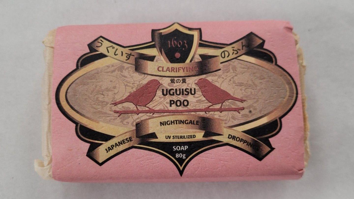 A bar of soap in pink and white packaging. On the cover it reads Uguisu Poo Japanese Nightingale Droppings