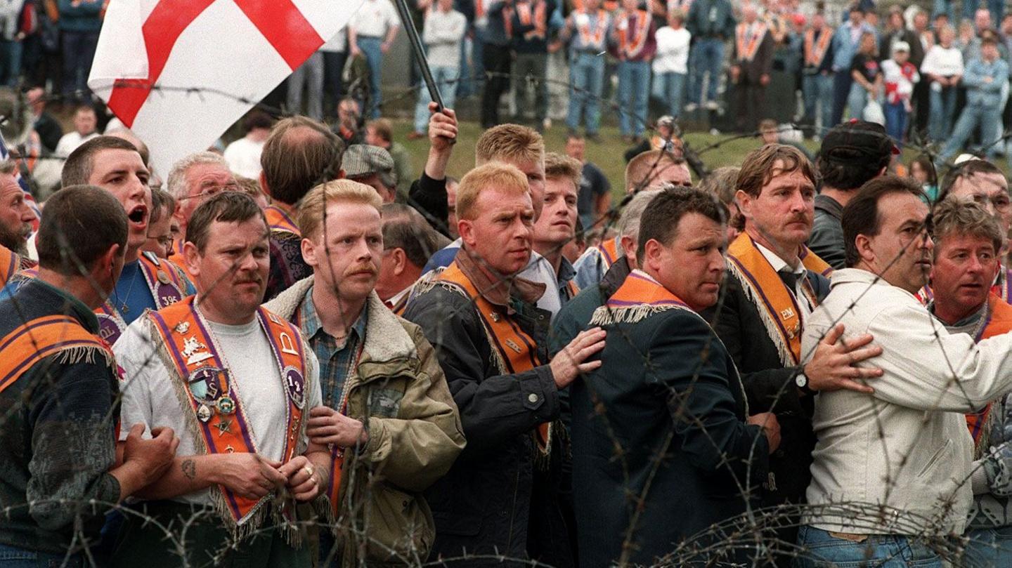 Members of the Orange Order stand behind barbed wire. 