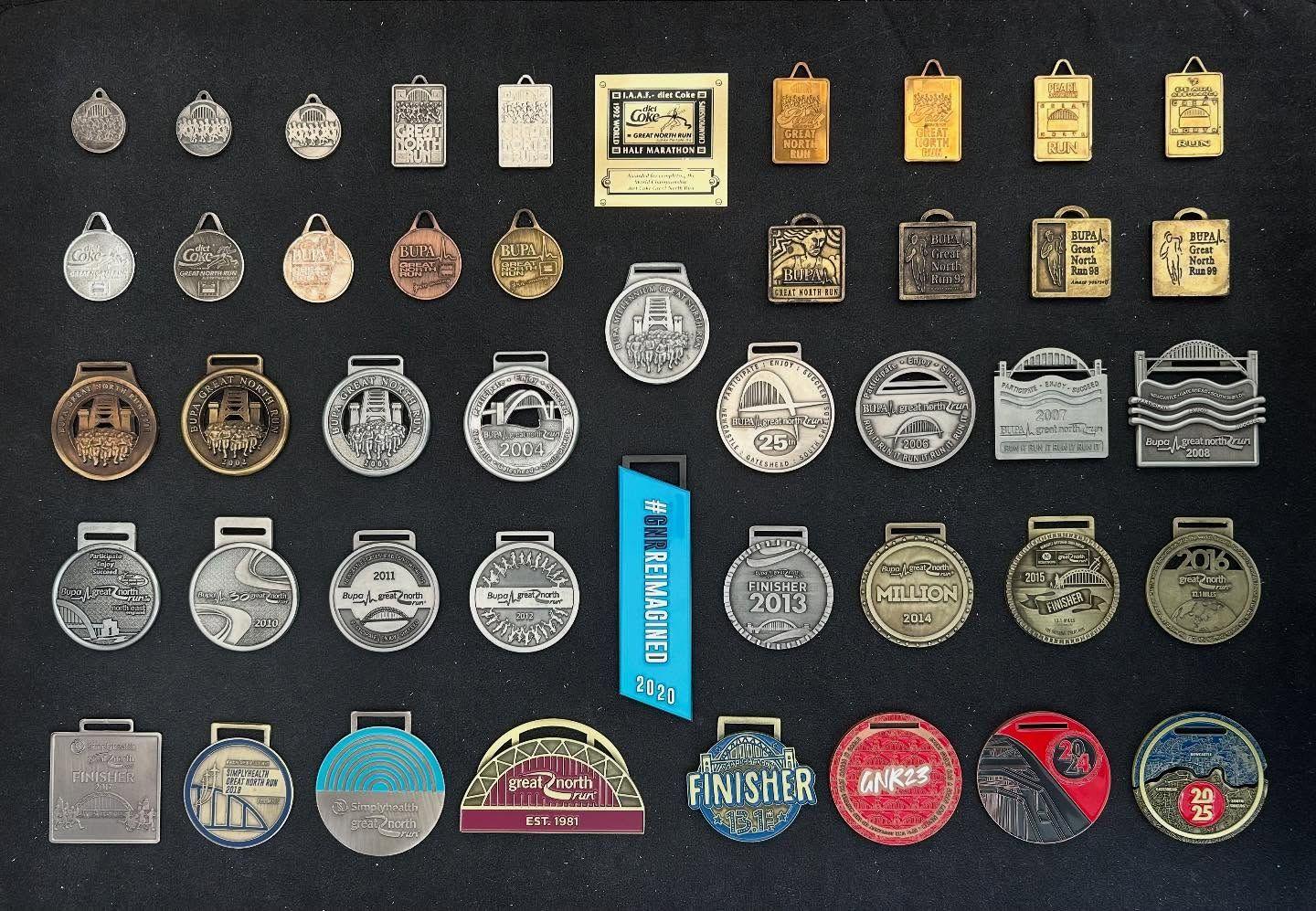 A collection of medals of various shapes including circular, rectangle and square, and various colours displayed against a black background.