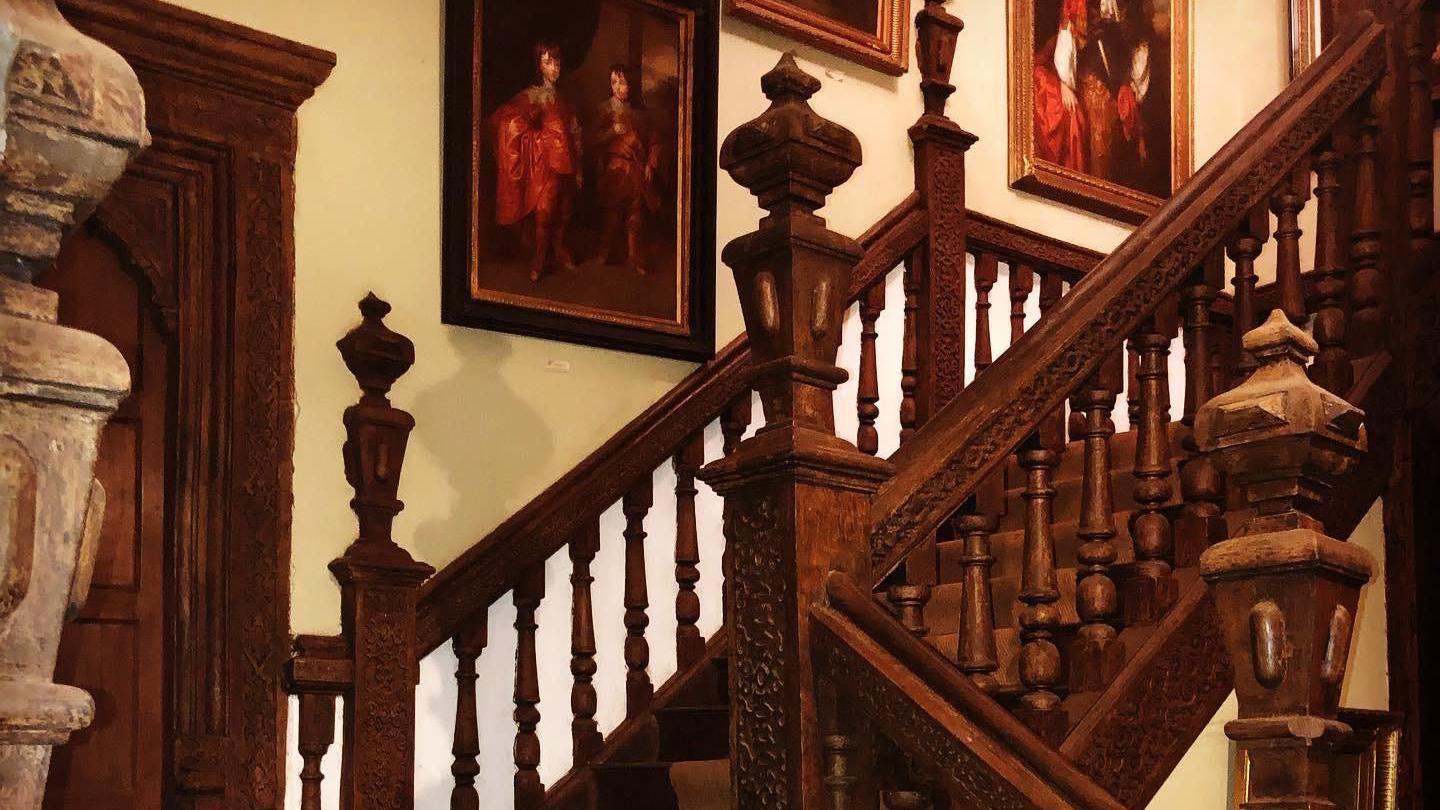 Wooden staircase with paintings on wall and a stone pillar to the left