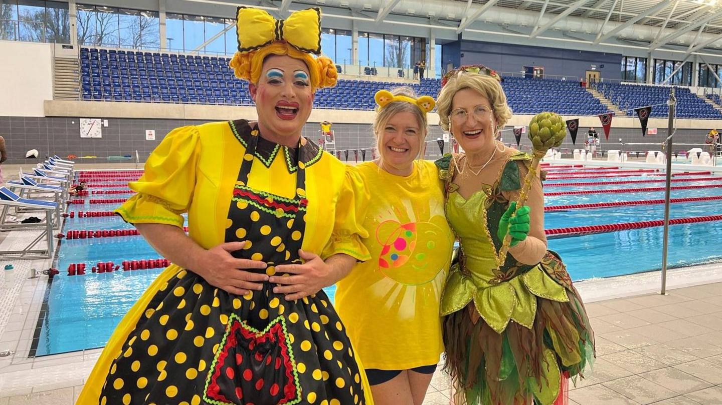 Sam Rabone from pantomime Jack & The Beanstalk is in a yellow costume on the left with Gill Jordan, better known as Doreen Tipton, on the right also dressed up, in green. Swimmer Kath Stanczyszyn is wearing a yellow t-shirt in the middle.