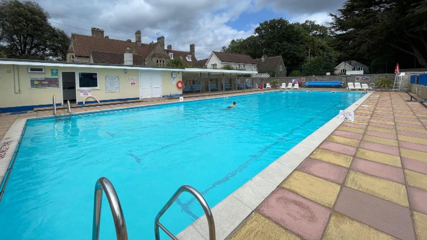 An outdoor pool with a swimmer swimming lengths to keep fit.