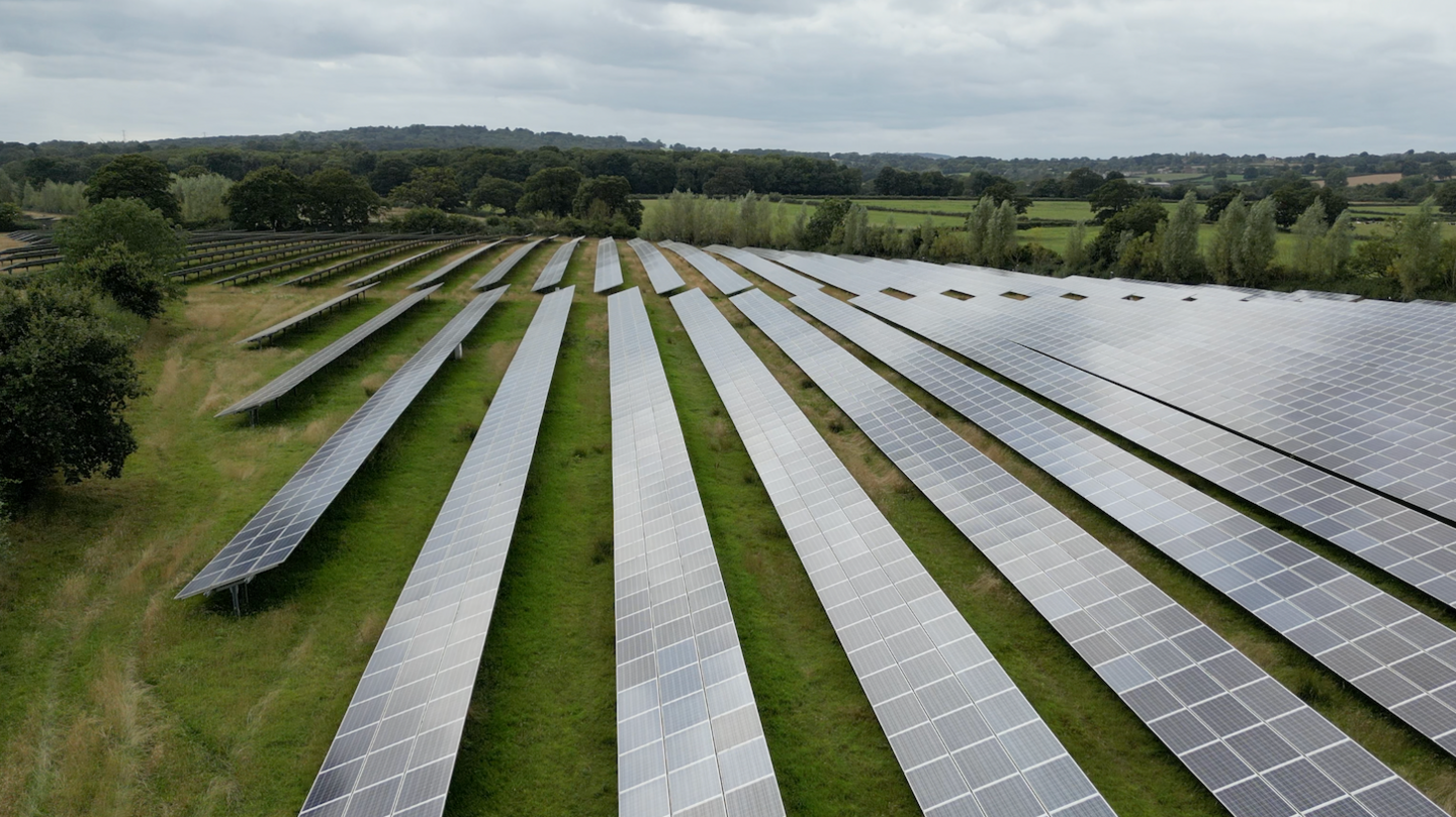 Solar panels on a field near Frome, seen from the air, on a field ringed by trees