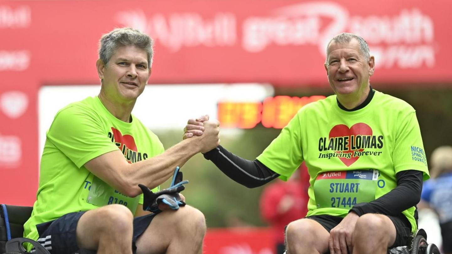 Two men in wheelchairs holding hands by the finish line of the Great South Run