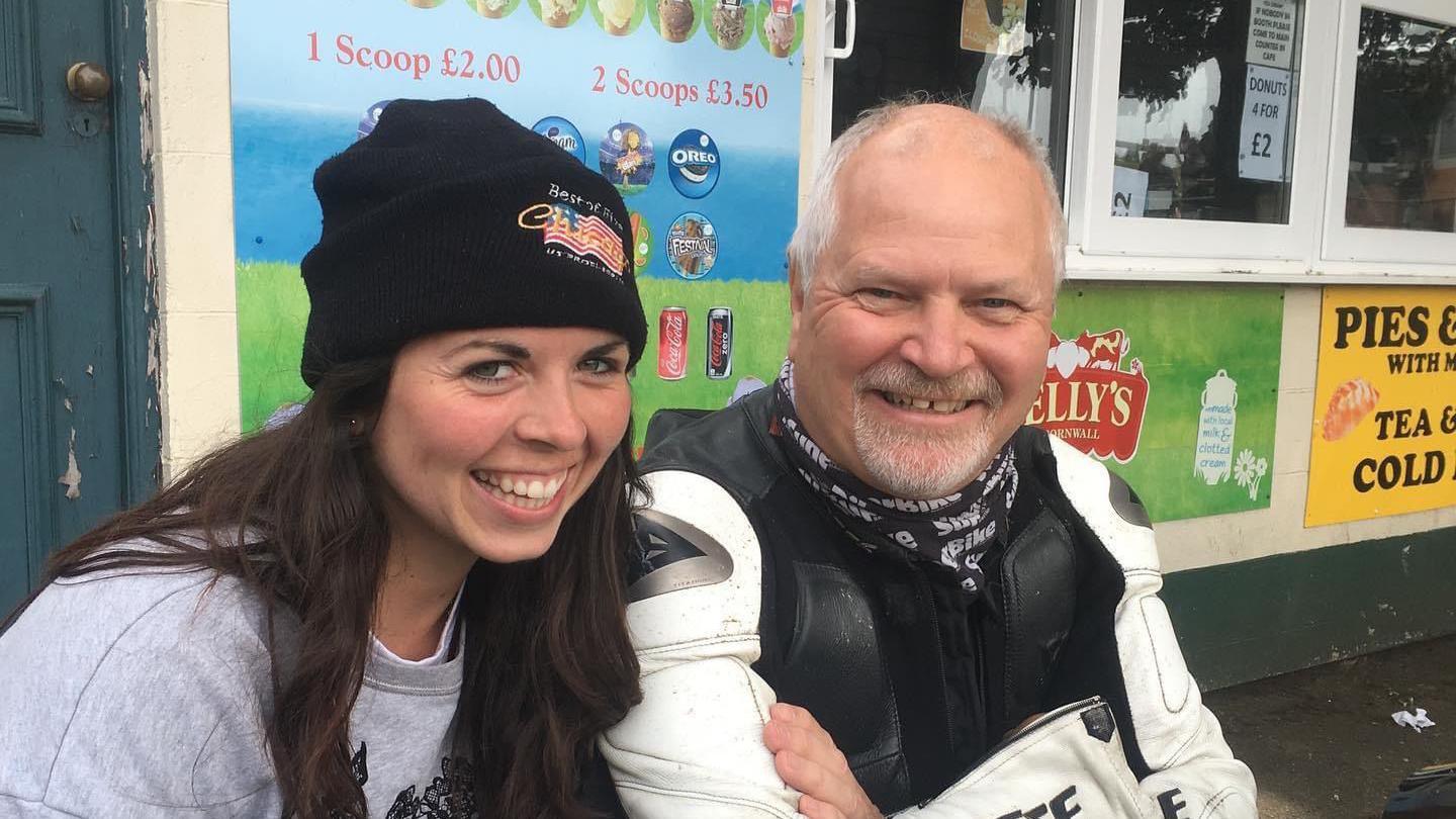 A woman in a black beanie hat and and a man in motorcycle leathers