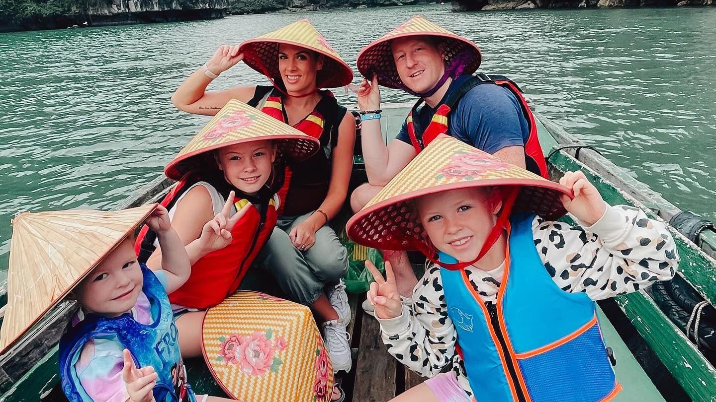 The family on a boat with traditional Thai hats on 