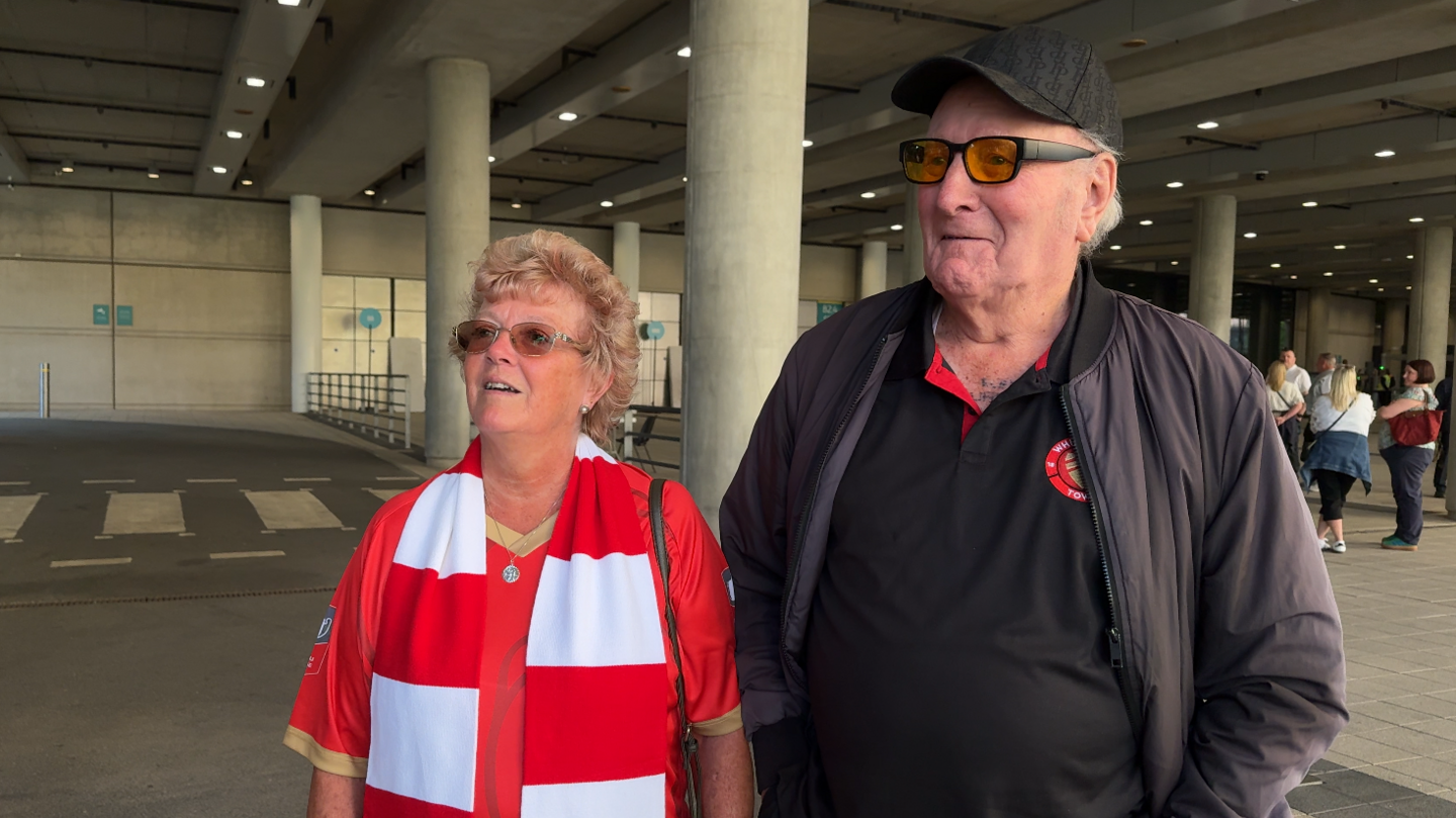 A man and a woman outside a football stadium.