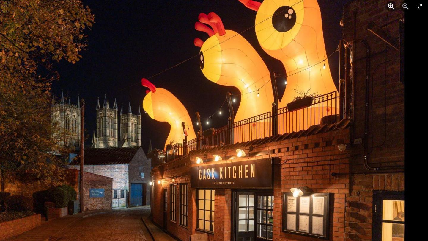 Three orange single-eyed with red antennas above a restaurant labelled Cask Kitchen.