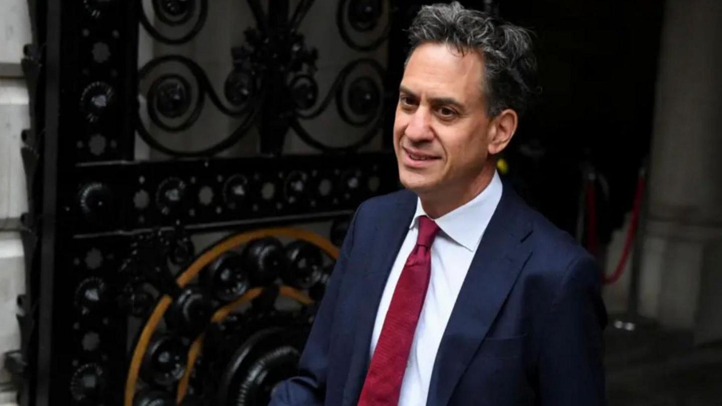 Energy Secretary Ed Miliband, standing in front of an ornate metal gate. 