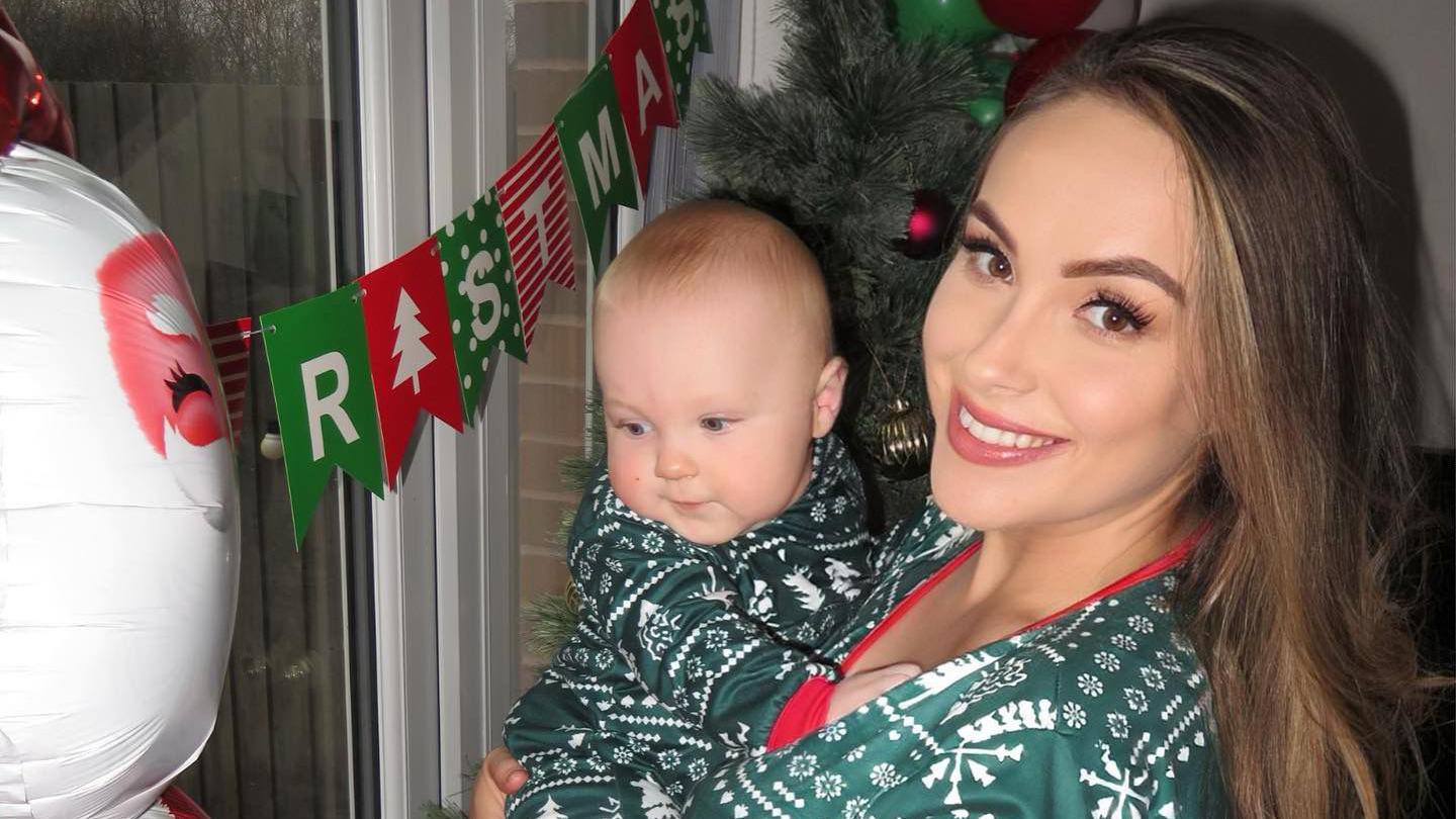 Emma and Leo in christmas jumpers. Leo is looking at an inflatable snoman and there is a christmas banner in the window behind them 