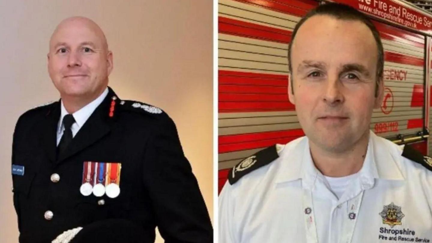 A bald headed man in black fire service uniform and a man with dark hair in a white fire service shirt