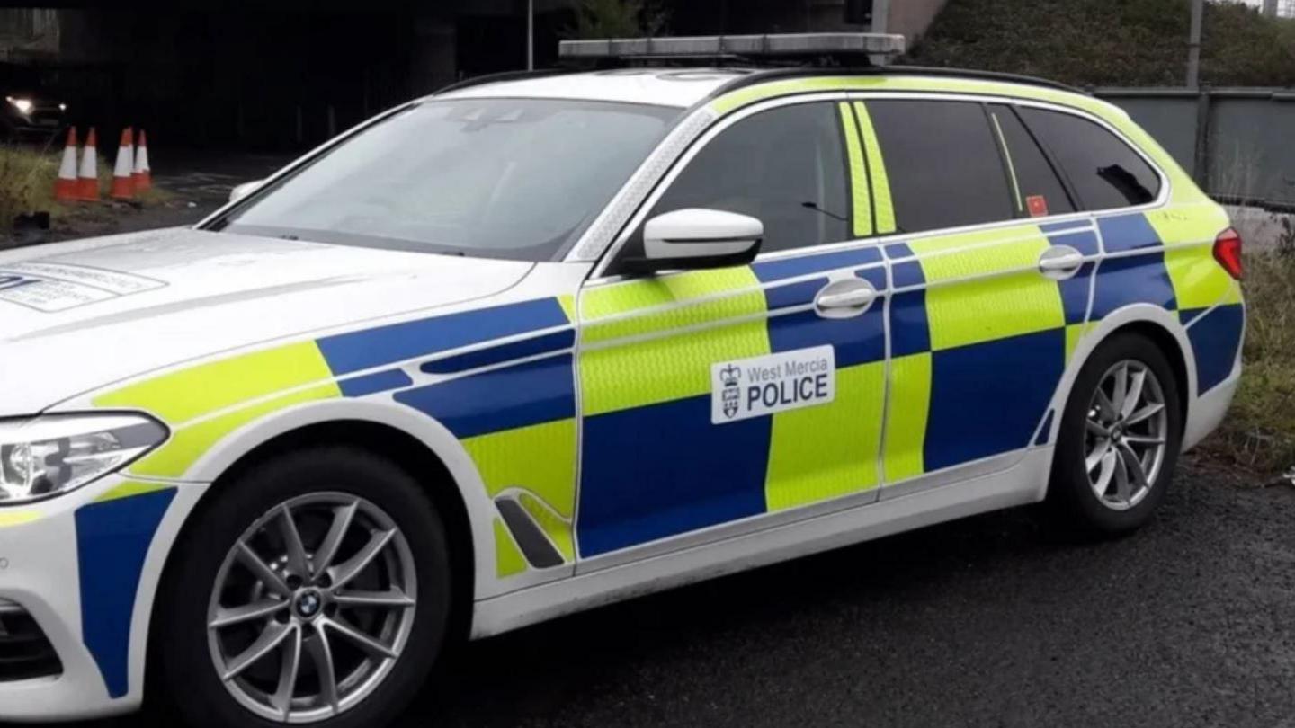 A West Mercia Police car. It is an estate car with bright blue and green markings. There is also a West Mercia Police logo. 