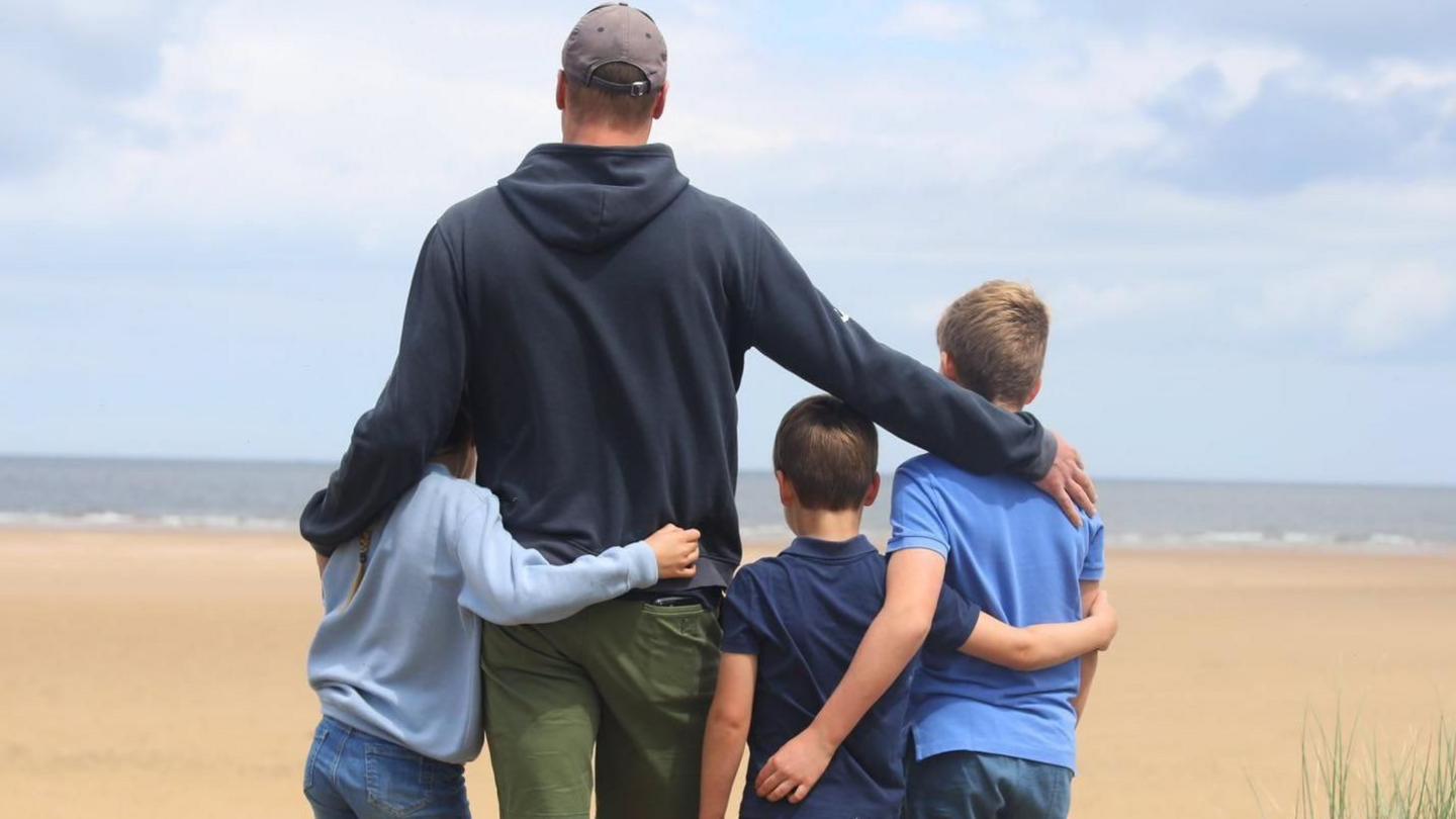 William and children on a beach looking out to sea