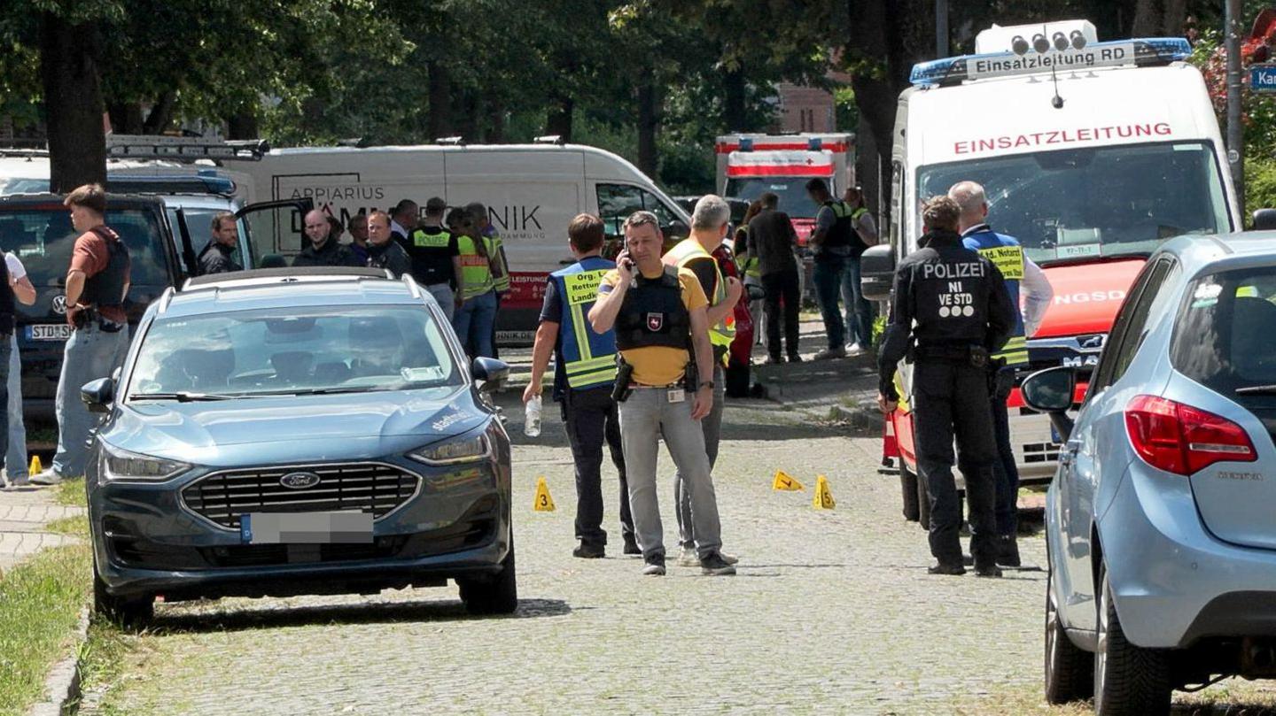 Crowds of emergency workers stand in the road following a shooting in Stade, northern Germany. 