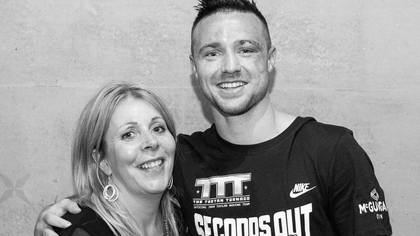 Photographer Jennifer Charlton (left) with taller boxer Josh Taylor (right), who has arm around her, both smiling.