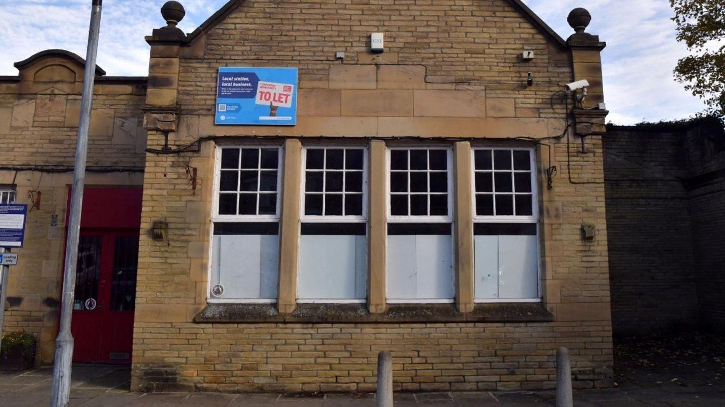 Empty shop unit at a station with four boarded up windows and a to let sign