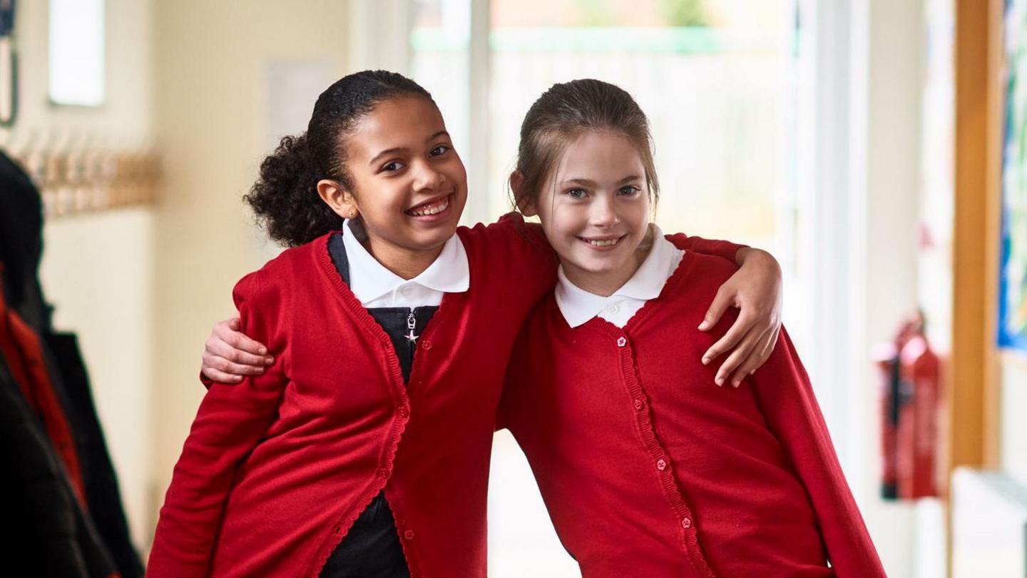 Two happy school girls hugging.