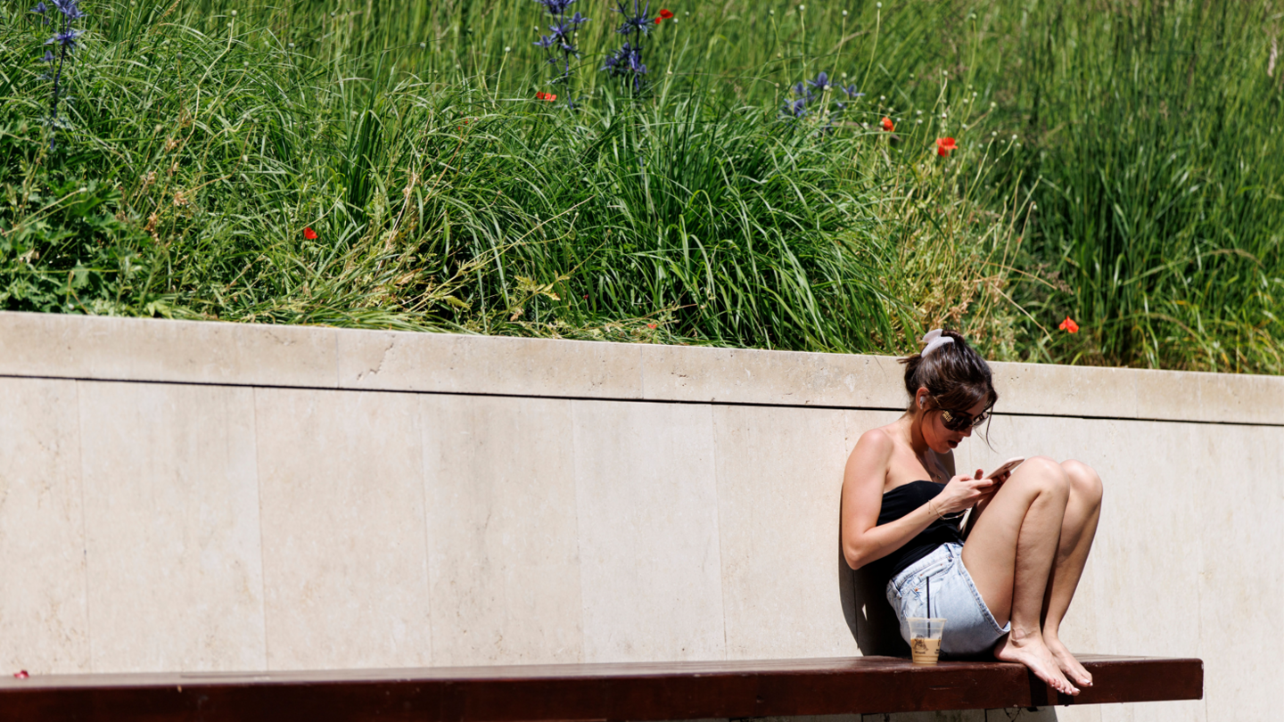 A person enjoys the sunshine and warm weather at United States Embassy Park in London