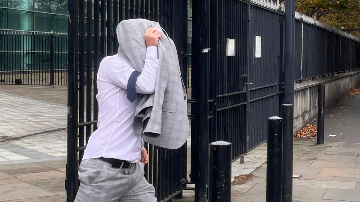 Christopher Morrow leaving Laganside Court covering his head with his jacket