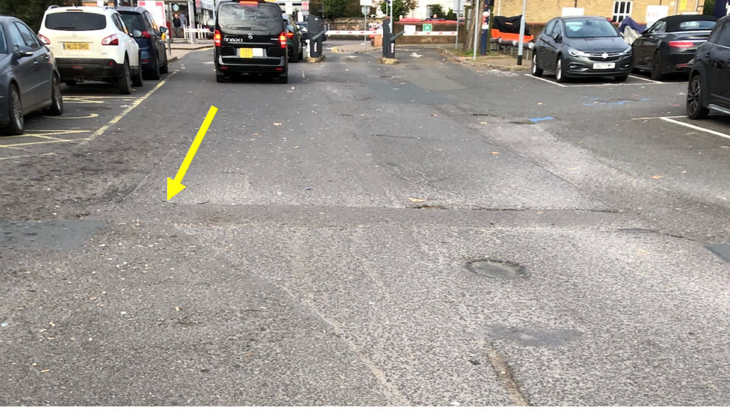 Station car park with uneven surfaces- cars parked on either side 