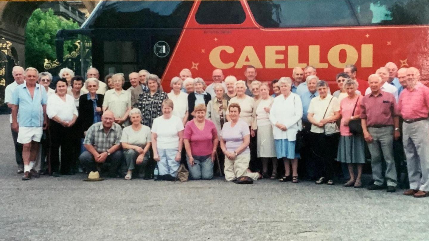 Aelodau'r clwb yn sefyll o flaen bws