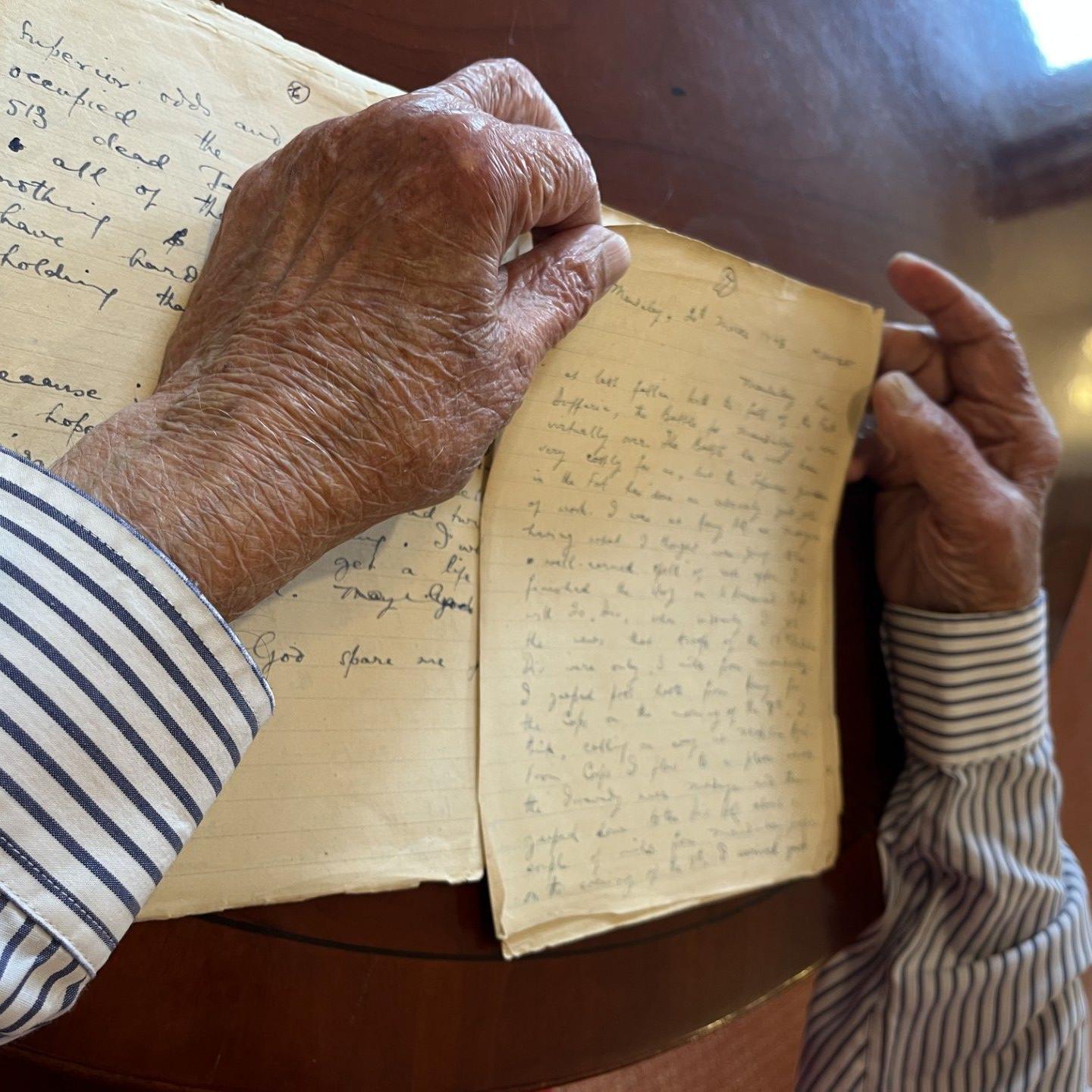 An image from Yavar's diary on 20 March 1945, the day Fort Dufferin fell. Also visible are Yavar's arms, in pinstriped shirtsleeves and his hands resting on a wooden table holding the pages 
