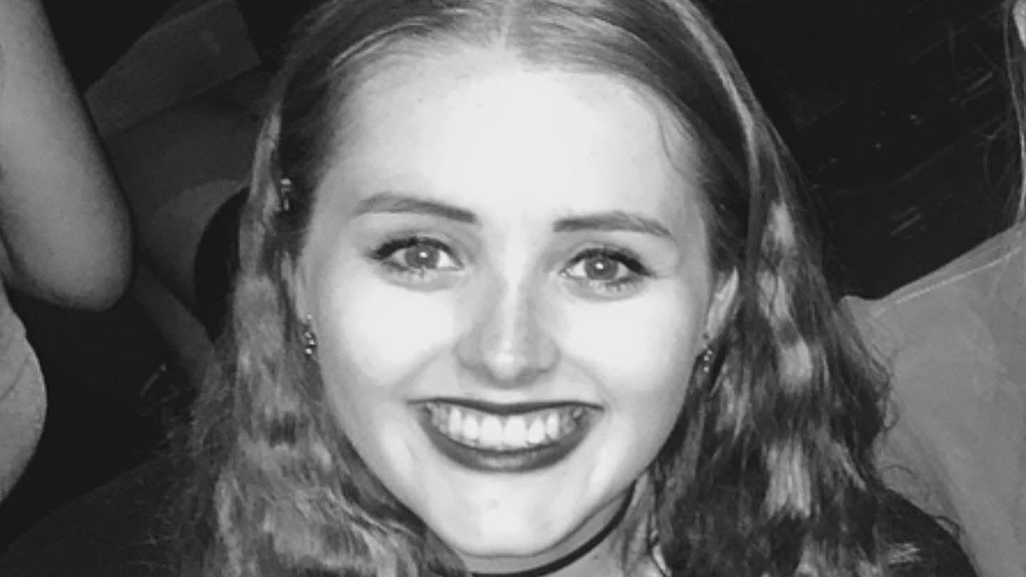 Black and white image of Grace Millane, a young woman who has wavy hair and is smiling.