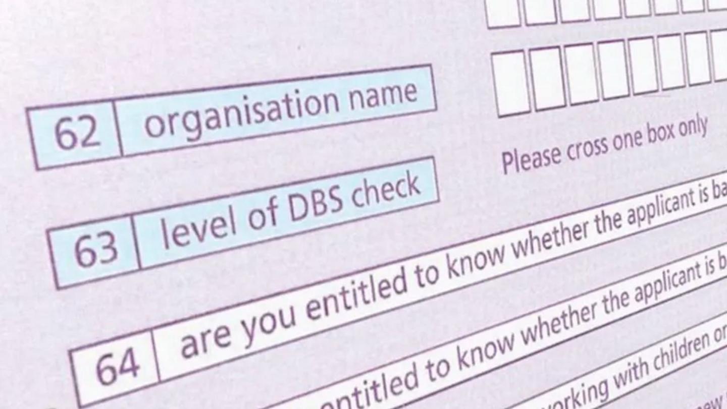A still image of an online DBS form. The words 'level of DBS check' are visible. The form is coloured shades of blue and purple.