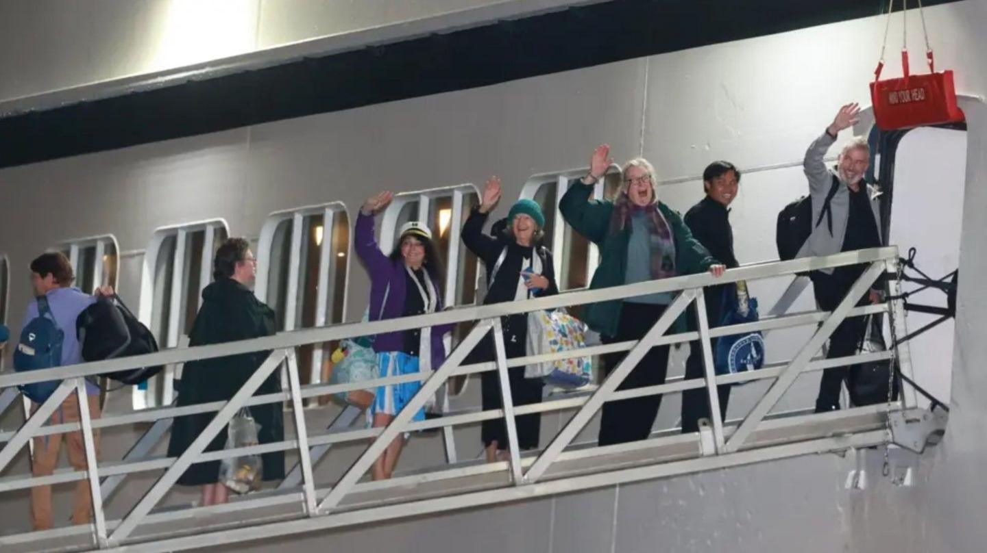 People waving as they board a cruise ship