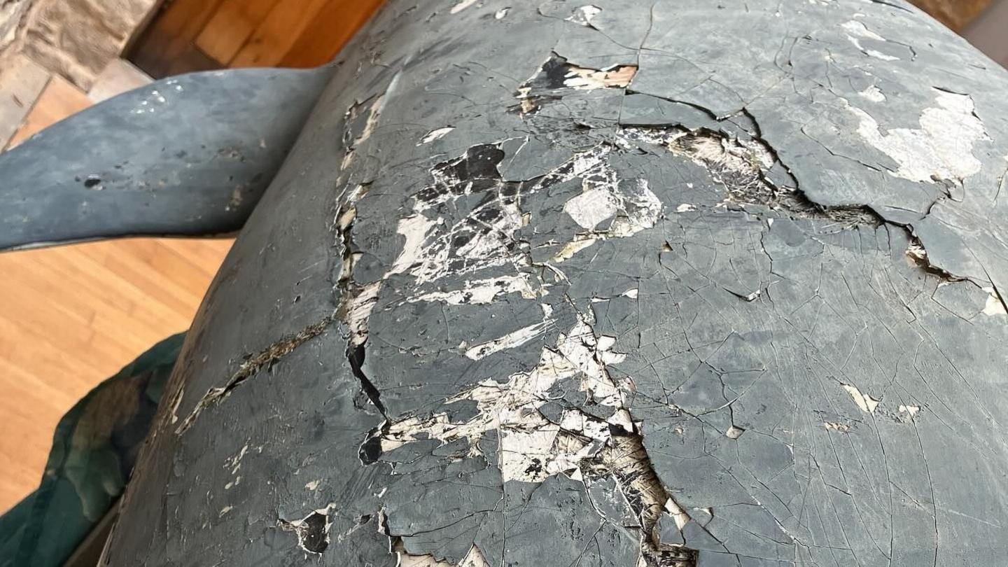 The cracked and damaged surface of the dolphin sculpture