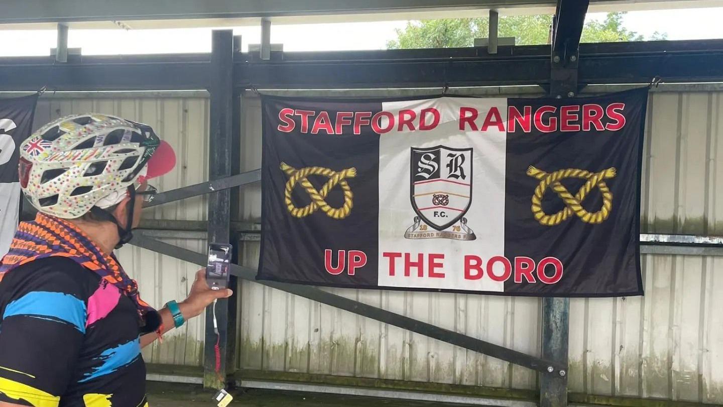 Timmy Mallet facing a Stafford Rangers flag