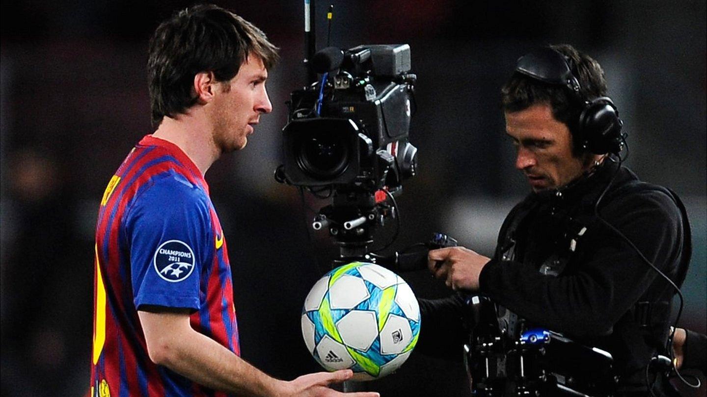 Barcelona's Lionel Messi leaves the pitch after a Champions League game, followed by a cameraman