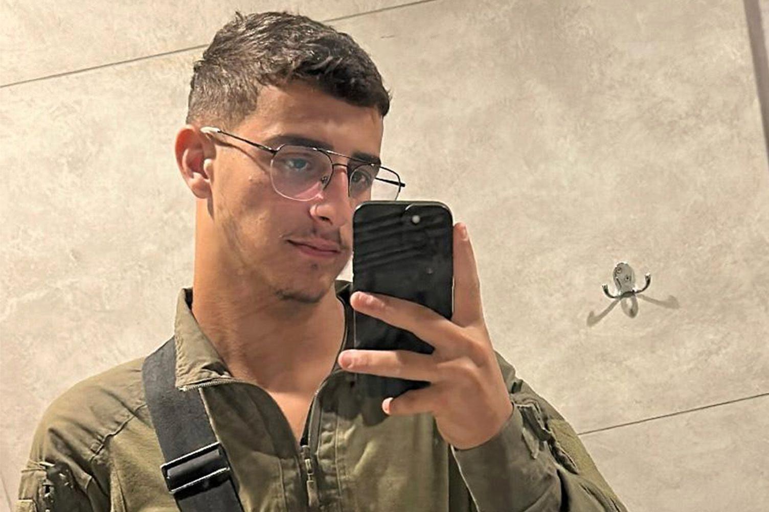 Selfie photo of IDF infantry soldier Shimon Malka. He has short brown hair, is wearing glasses and has a small beard on his chin. He is holding his mobile phone taking selfie in a mirror.