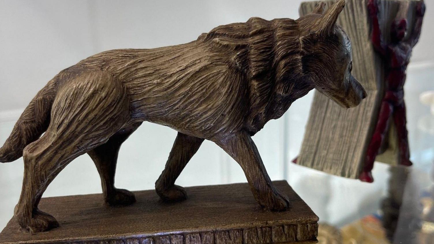 This image shows a detailed wooden sculpture of a direwolf, representing House Stark