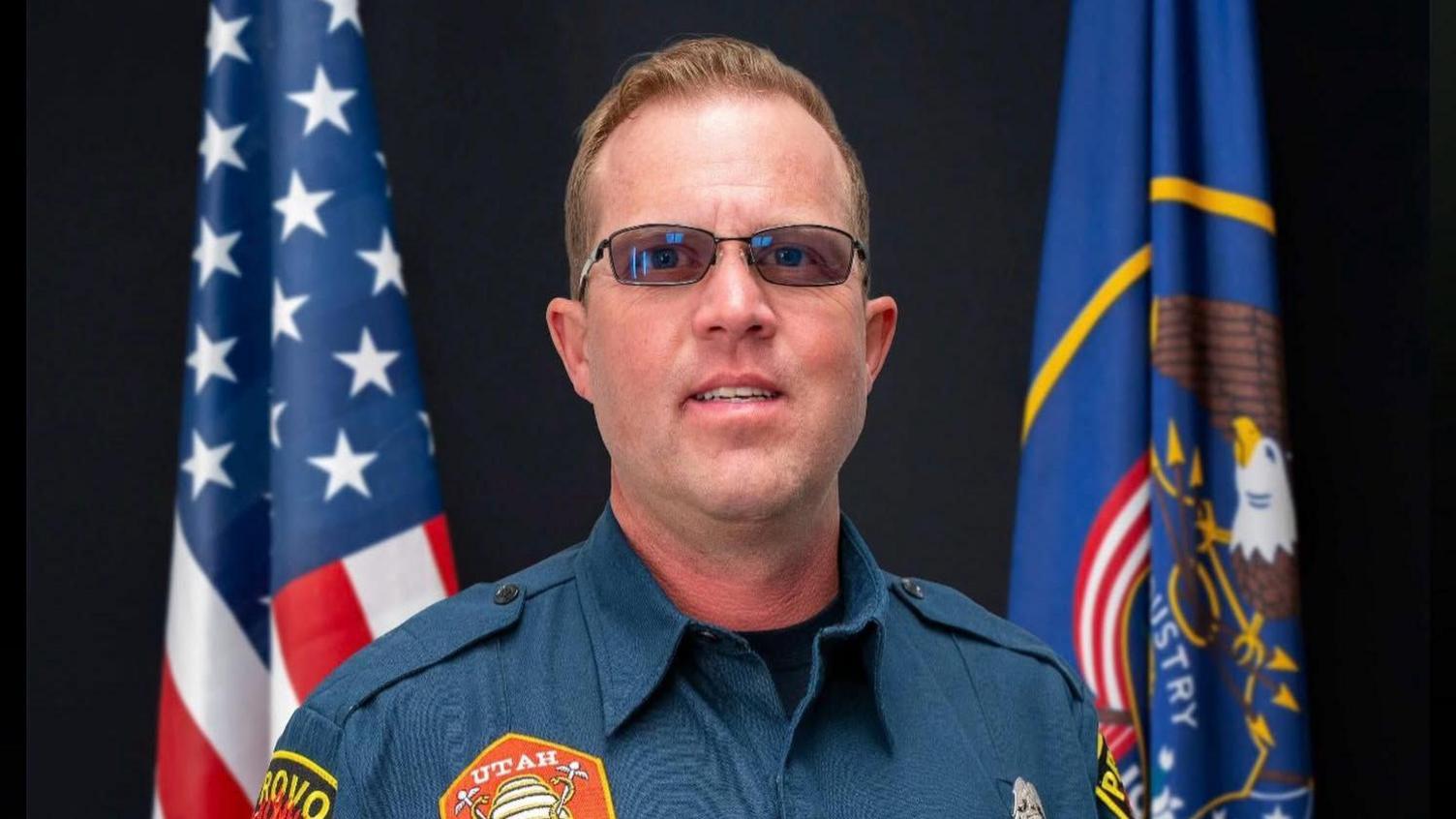 An image published by Provo Fire & Rescue shows Spencer Long in his firefighter uniform in front of two flags