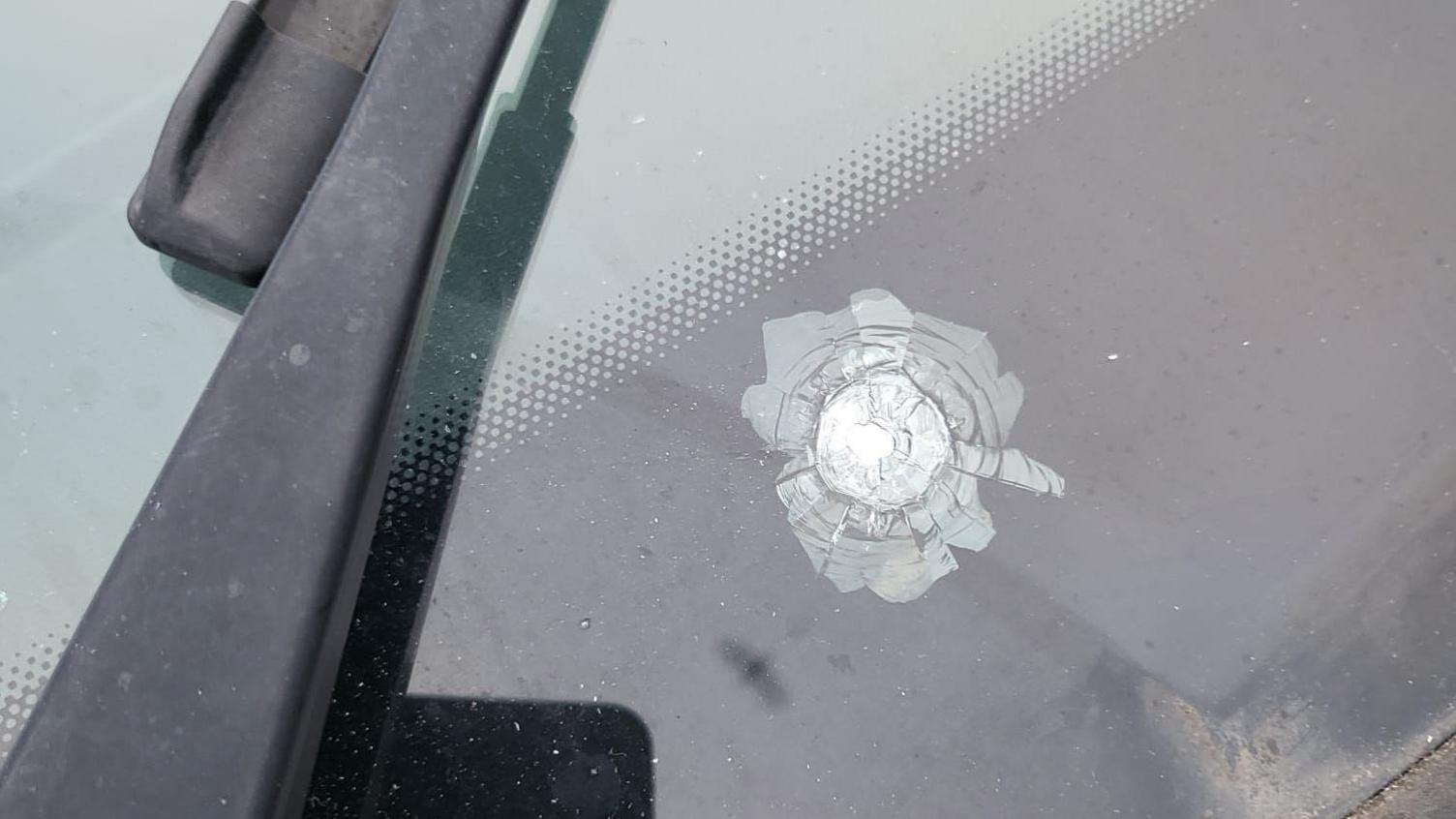 A close-up of a pellet mark on the windscreen of a car.