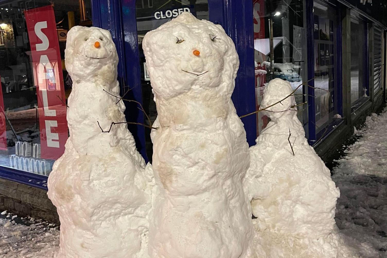 Three snowmen outside a shop